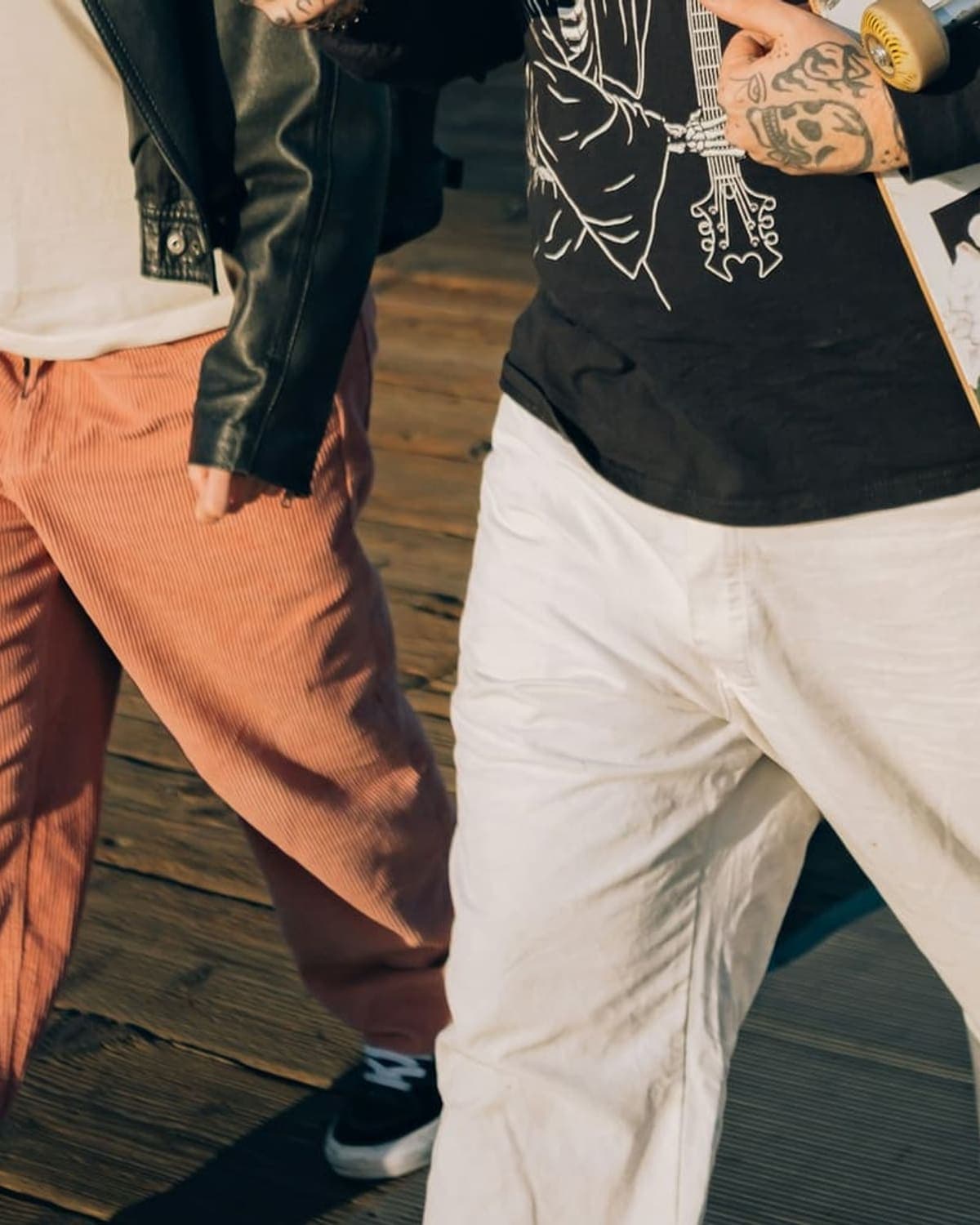 Two people walking with a skateboard, orange and white pants